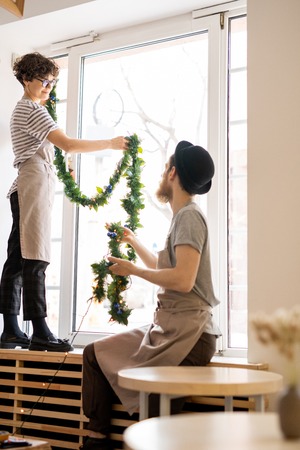 Cafe staff decorating window with tinselの写真素材
