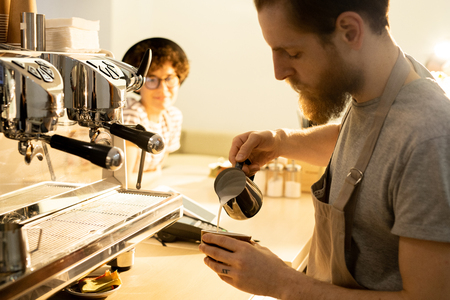 Bartender pouring milk into coffeeの写真素材