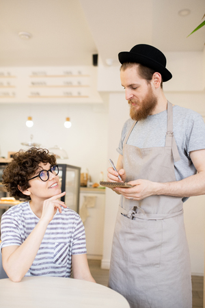Hipster waiter in hat taking orderの写真素材