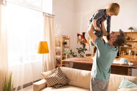 Happy father raising son at cozy homeの写真素材