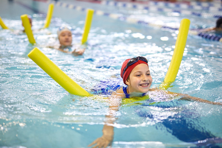 Little girls with swimming noodles in poolの写真素材