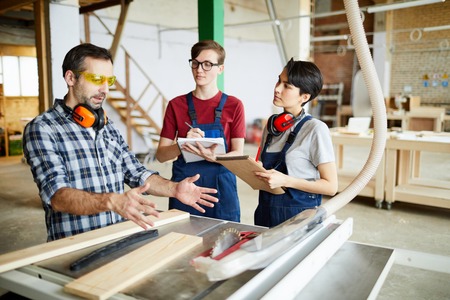 Skilled carpenter working with interns