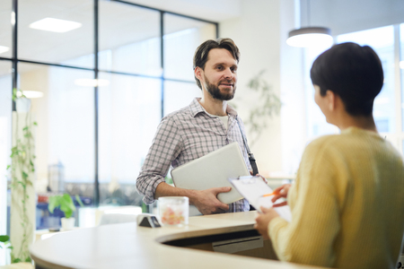 Young programmer talking to hotel receptionistの写真素材