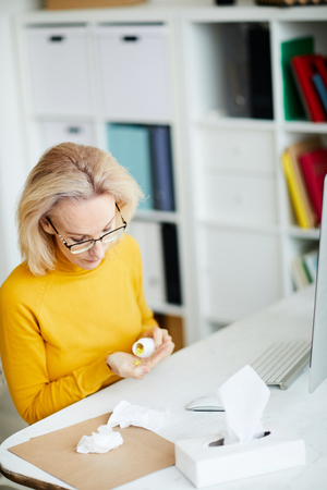 Woman Taking Pills at Workplaceの写真素材