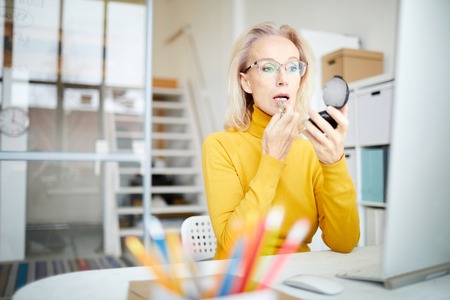 Mature Woman Doing Makeup at Workの写真素材