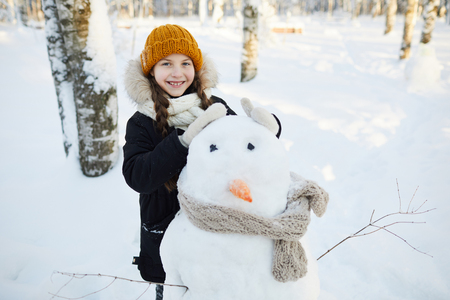 Little Girl Posing with Snowmanの写真素材