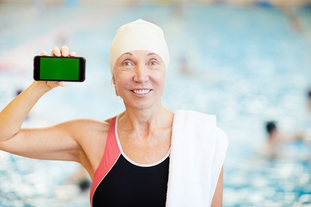 Senior Woman Presenting Smartphone in Poolの写真素材