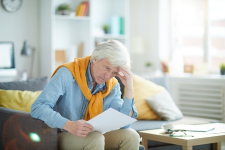 Frustrated Senior Man Looking at Documentの写真素材