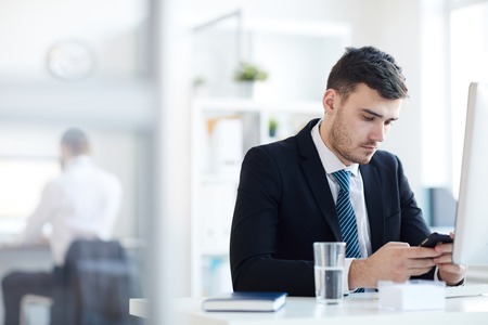 Man texting by workplaceの写真素材
