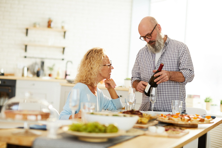 Senior man talking about wine to ladyの写真素材