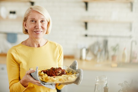 Careful mature lady with cooked meatの写真素材