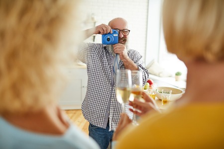 Cheerful man taking photo of friendsの写真素材