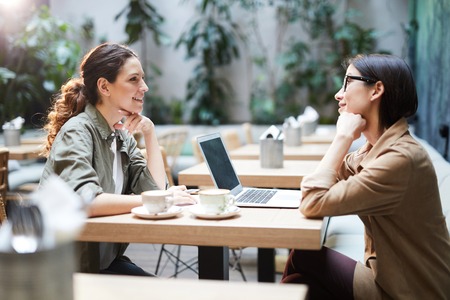 Business ladies discussing project in cafeの写真素材