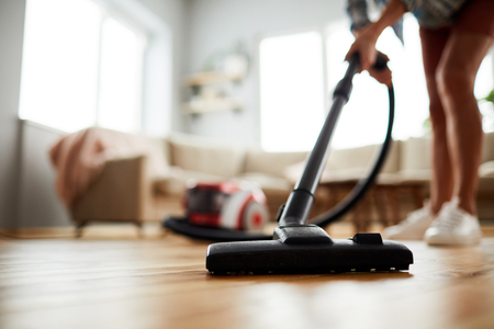Close-up of unrecognizable woman vacuuming floor at homeの写真素材