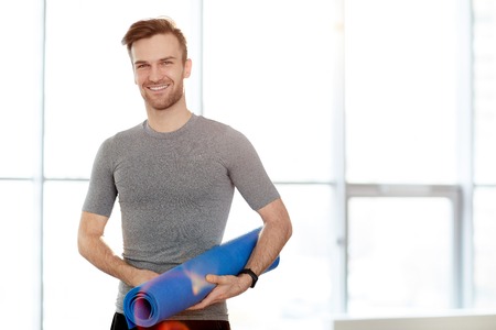 Handsome yoga instructor with exercise matの写真素材