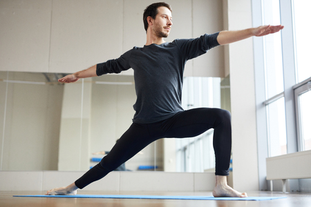 Slim man doing standing yoga poseの写真素材