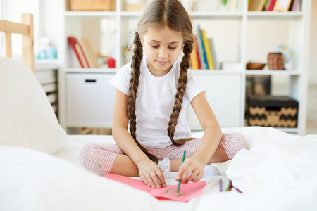 Girl Drawing Pictures on Bedの写真素材