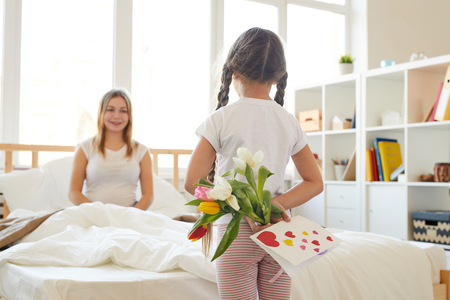 Girl Surprising Mom with Flowersの写真素材