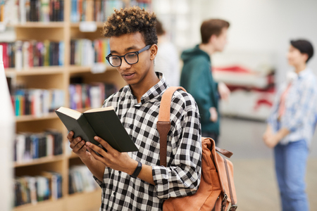 Intelligent guy reading book in libraryの写真素材