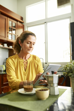 Middle-aged woman reading e-bookの写真素材