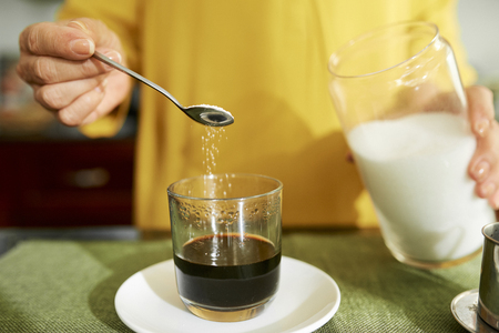Woman adding sugar in her espressoの写真素材