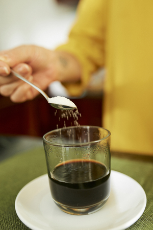 Woman adding sweetener in coffeeの写真素材