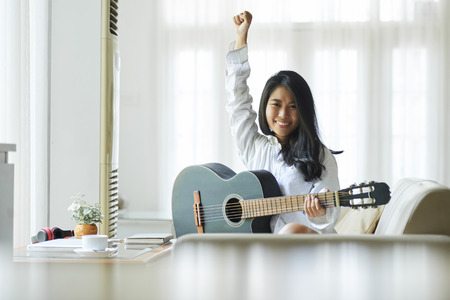 Cheerful woman playing guitarの写真素材