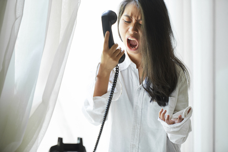 Woman shouting in telephone receiverの写真素材