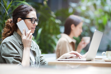 Freelance manager talking on phone while using laptopの写真素材