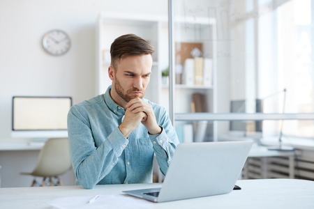 Pensive Young Man Using Laptopの写真素材