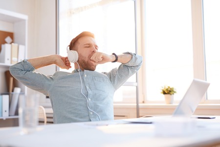 Young Man Yawning at Workplaceの写真素材