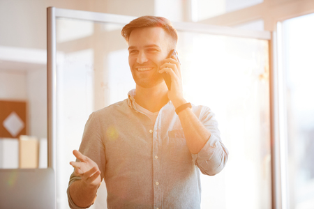 Contemporary Businessman Speaking by Phone in Sunlightの写真素材