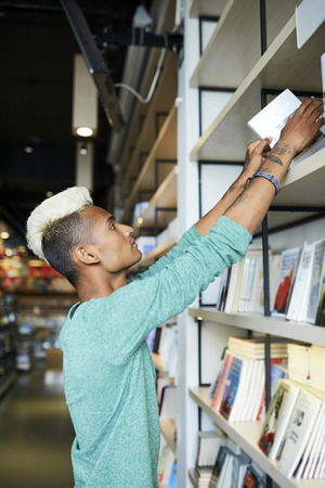 Bookstore employee putting books on shelfの写真素材