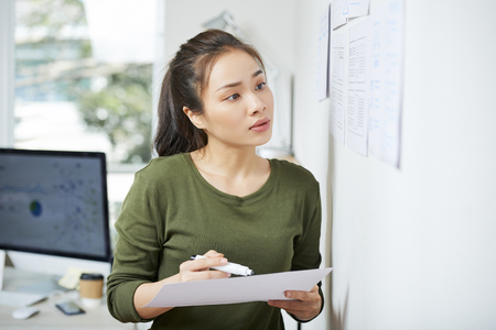 Asian lady comparing data in papersの写真素材