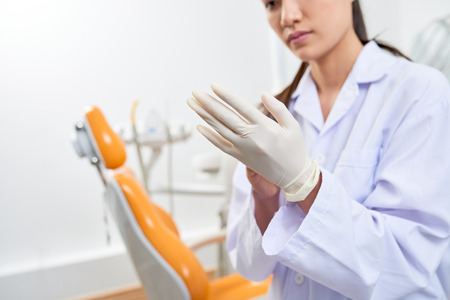 Dentist putting on latex glovesの写真素材