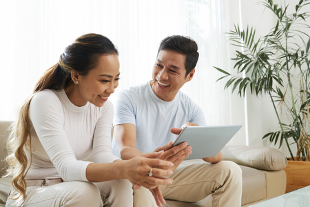 Cheerful couple watching show on tablet computerの写真素材