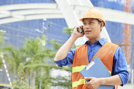 Engineer has a business talk on the phone outdoors