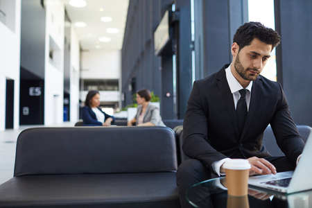 Handsome businessman using laptop in lobbyの写真素材