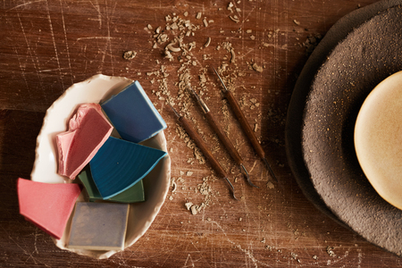 High angle view of handmade ceramics pieces in bowl, stack of textured plated and various craft tools for mouldingの写真素材