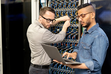 Multi-ethnic IT engineers setting up computer cluster