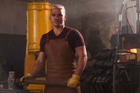 Brutal blacksmith working with heavy hammer