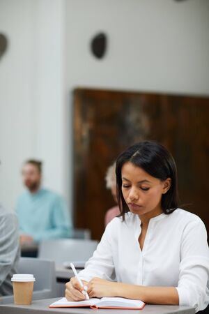 Mixed-Race Businesswoman Writing in Classの写真素材