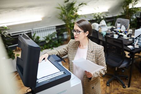 High angle portrait of young businesswoman scanning documents while working in office, copy spaceの写真素材