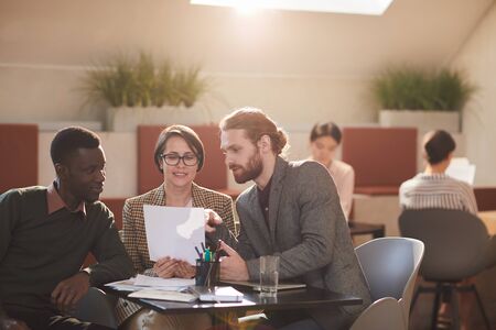 Warm toned portrait of group of people working in cafe, copy spaceの写真素材