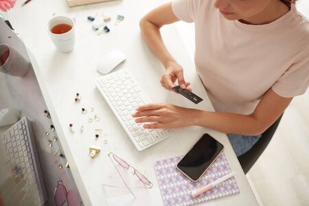 Above view of woman in casual tshirt sitting at table and checking order before online paymentの写真素材
