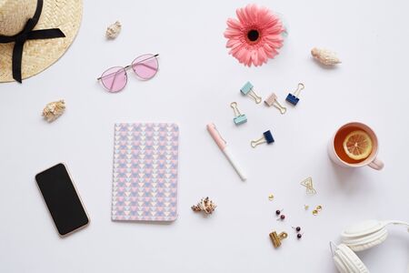 Female designers background with creative diary, clippers, cup of lemon tea, headphones, flowerの写真素材