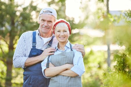 Waist up portrait of senior couple smiling at camera and posing while working at farm, copy spaceの写真素材
