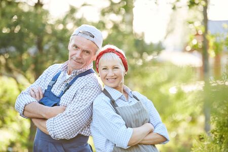 Waist up portrait of senior couple smiling at camera and posing confidently while working at farm, copy spaceの写真素材