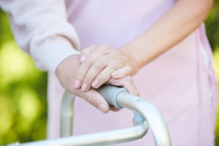 Closeup of caring wife holding hand of husband using walker, copy spaceの写真素材