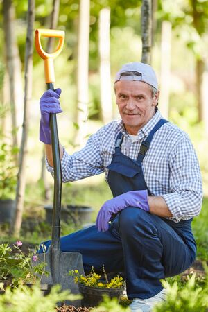 Full length portrait of mature man working in garden and looking at cameraの写真素材